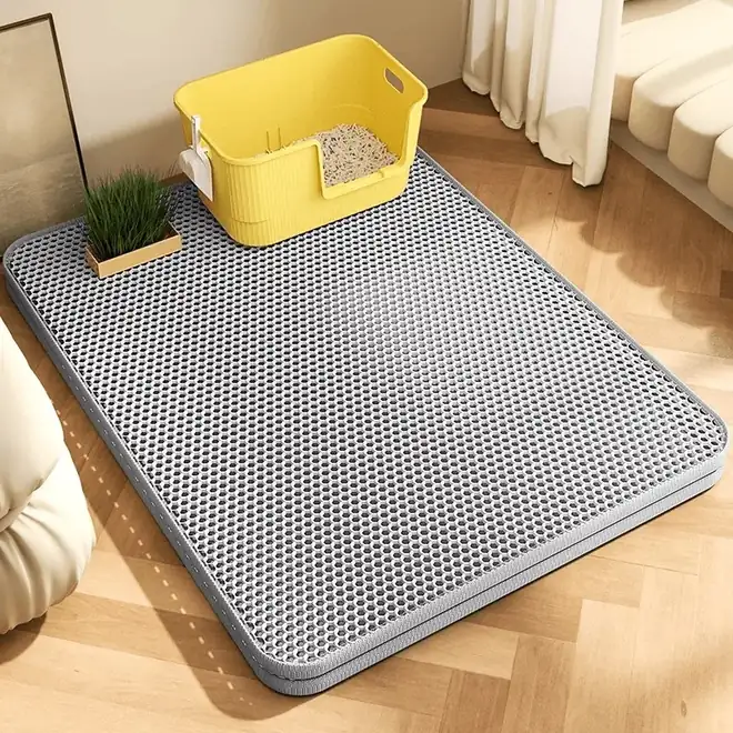 Tapis de litière gris posé devant un bac sur parquet