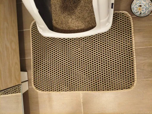 Tapis de litière kaki installé devant une maison de toilette