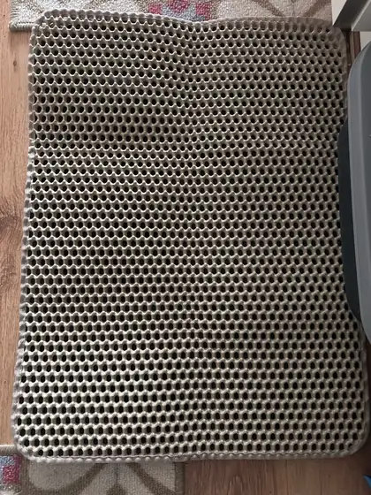 Tapis de litière Minopatte posé sur un parquet, à côté d'un bac à litière gris foncé